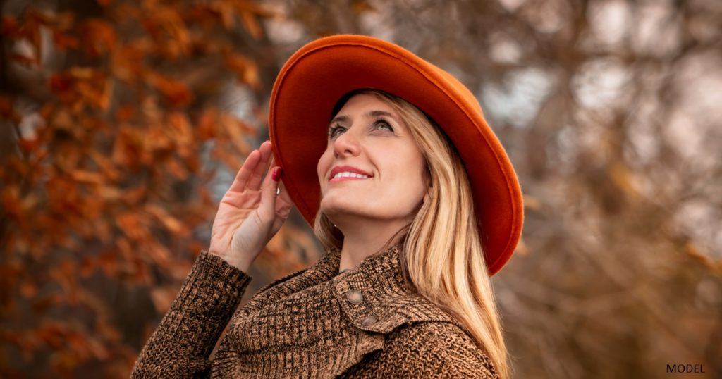 Woman enjoying the Fall weather outdoors wearing a hat