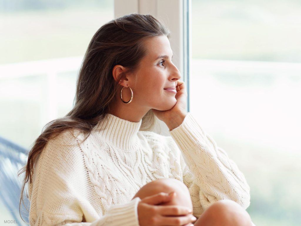 Woman with smooth skin looking out the window (MODEL)